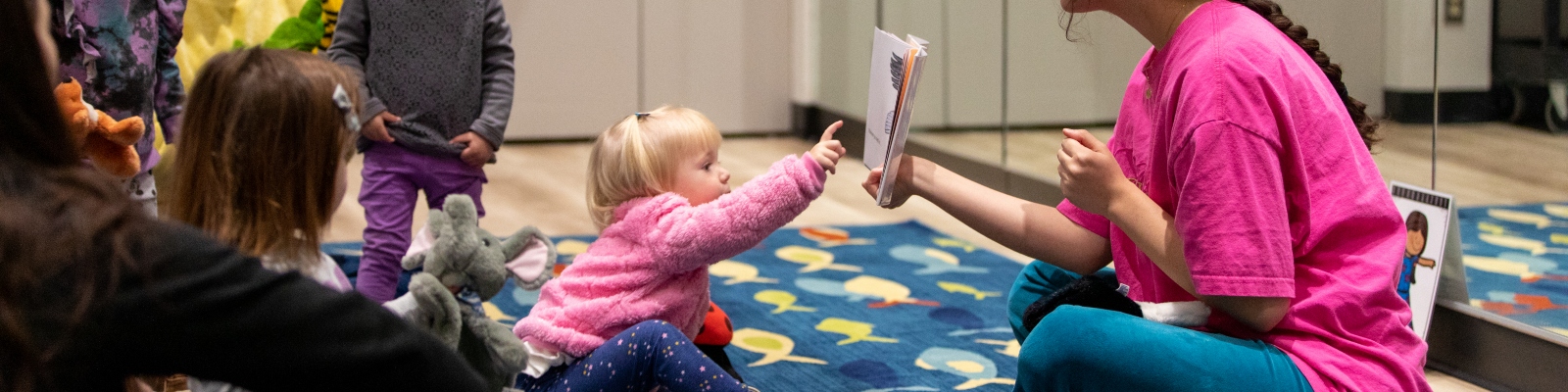 A young child reaching out and touching a book