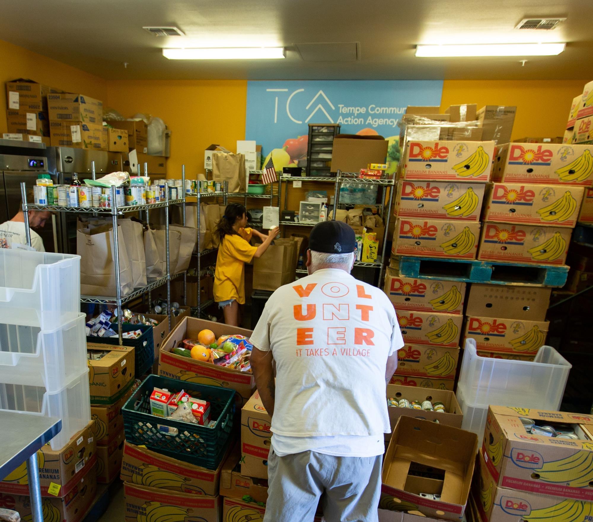 Volunteers add food donations to pantry filled with food and canned goods