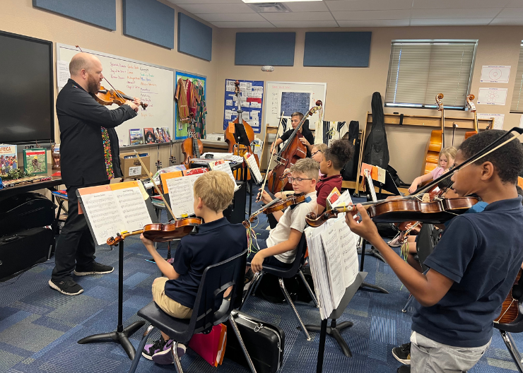 A music clinician teaches an orchestra class of middle school students.