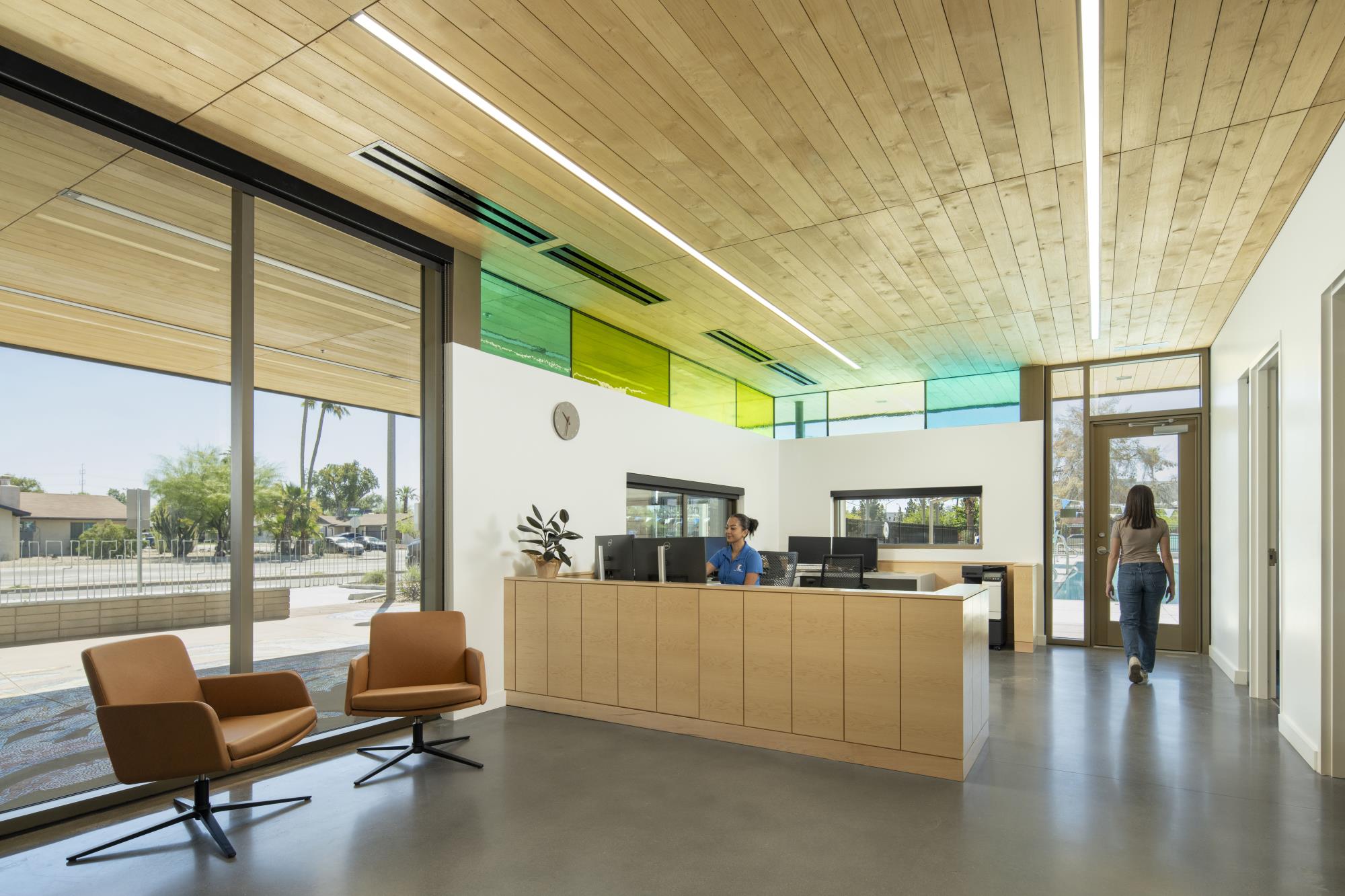 Image of a front desk reception area with green and turquoise stained glass in the background.